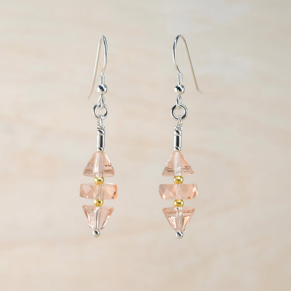Pair of earrings with pink and gold beads on a beige background