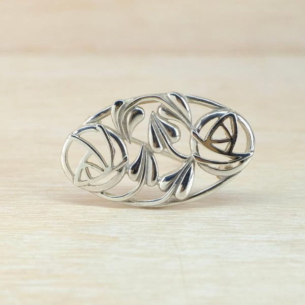 Silver brooch with intricate design on a beige background