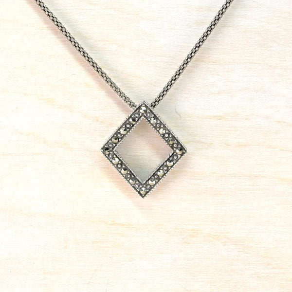 Necklace with a square pendant on a light wooden surface
