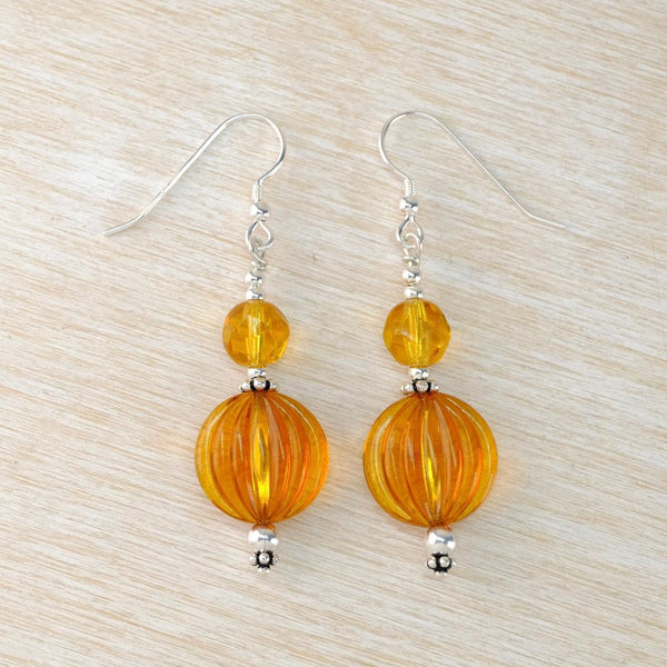 Pair of orange beaded earrings on a light wood surface