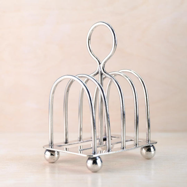 silver-plated toast rack with a round handle on a beige background