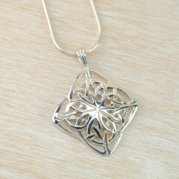 Silver Celtic knot pendant on a light wood surface