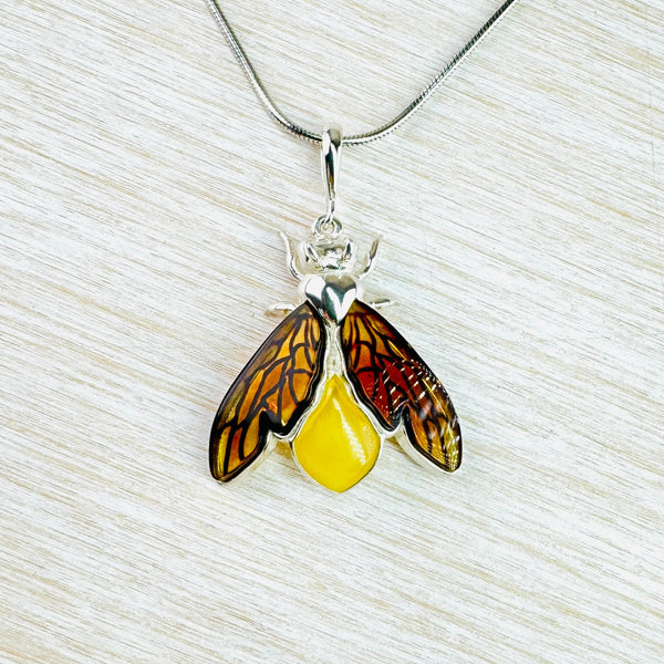 Gorgeous bee! The body is formed from an opaque yellow amber. Two wings, semi folded in, have more orange coloured clear amber set in sections to look really life like. The top of the bee's body, head, pincers and front legs are polished silver. Hanging off a plain long bale and a silver chain.