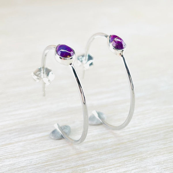 Fairly large silver hoops, with an opening at the back and a finer stem for the butterflies to slip over. At the front, about a third of the way round, two teardrop purple stones, surrounded by silver, sit on top of the hoop. The stones are purple/pink with metallic gold flecks running through.
