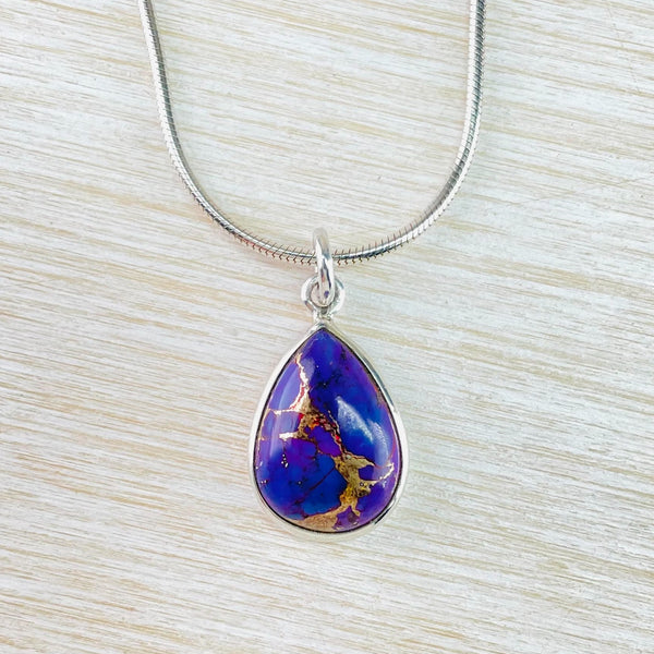 Very prettily marked tear drop shaped purple stone. Gold coloured patterns move down the stone looking a bit like a map of south america . Framed in silver and hanging off a circle silver bale with a chain threaded threw.