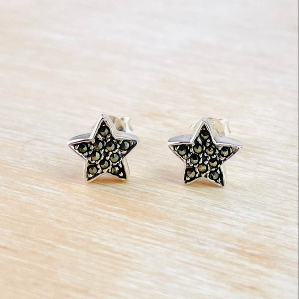 A pair of sterling silver stud earrings adorned with marcasite stones in a star shape, displayed on a light surface.