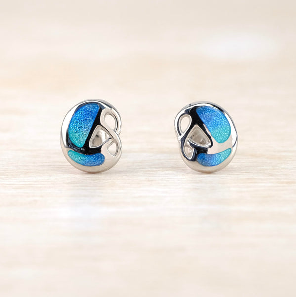 The overall shape is off circle. There are two blue/green enamel panels on the outer edges with a silver twist on the inner part.