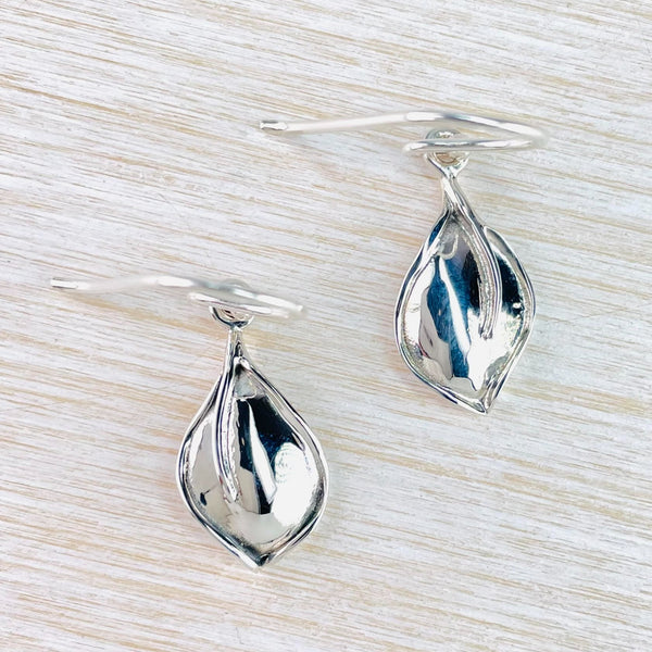 Shiny silver in a simple wide leaf shape with a single vein slightly off centre. They are slightly convex and hang off a hook.