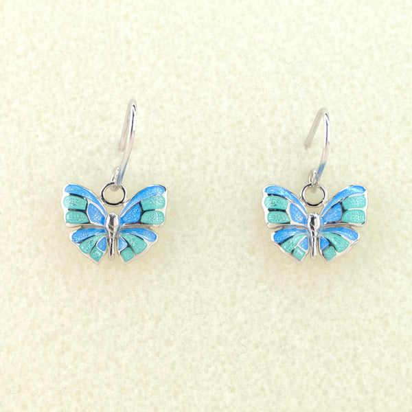 Butterfly design earrings with a silver body and silver edges and veins within the wings. Blue and pale green enamel forms the wings. Hanging off a silver hook.