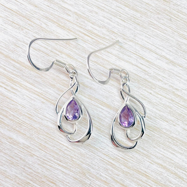 Light purple sparkly tear drop shaped stones are set within  shiny silver swirls, Three swirls each a little larger than the  other as you move down the earring.