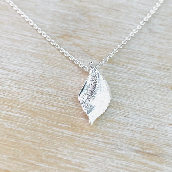 Satin silver in a vague leaf shape is set with a line of sparkly zirconia from the top to two thirds of the way down. Suspended from a link chain.