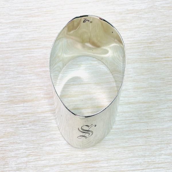 Plain shiny silver oval shaped napkin ring with an ornate S engraved on the narrow front.