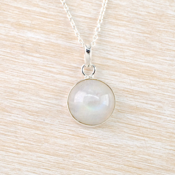 Very simple. A round opaque grey/blue moonstone is set in silver and hangs off a chain via a ring and polished bale.