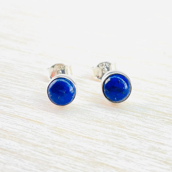 A deep dark blue round lapis stone is simply set in silver. The lapis has small gold, black and paler blue flecks.