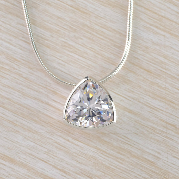 A rounded edge traingle - pointed bit facing upwards. The stone is clear shiny Cz surrounded with silver with a silver snake chain threaded through the back.