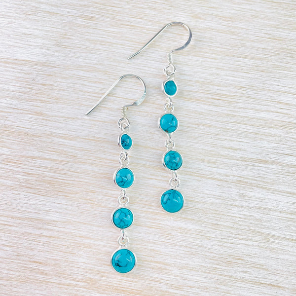 Four round turquoise stones, each set  in silver and linked by a round silver  ring, getting a little larger as you  move down the earring. The stones have delicate black crackle effect.