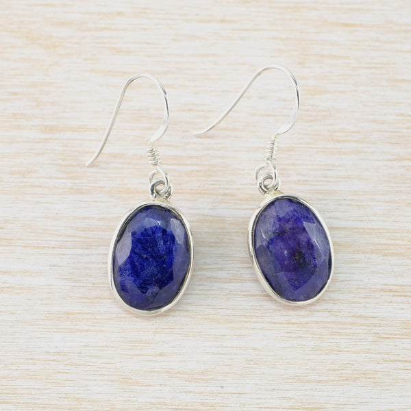 Oval faceted deep blue stones very simply set in polished silver hanging from a silver hook.