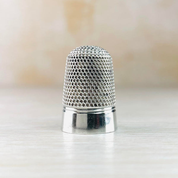 The top two thirds od the silver thimble is covered with little dots, the bottom third is plain high polished silver with a horizontal indent between the two.