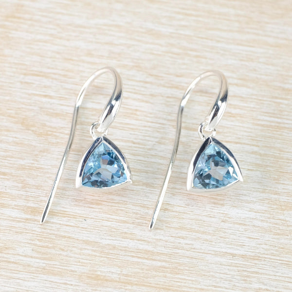 Bright blue cut stone, shaped in a rounded triangle shape surrounded in silver and hanging from a silver hook.