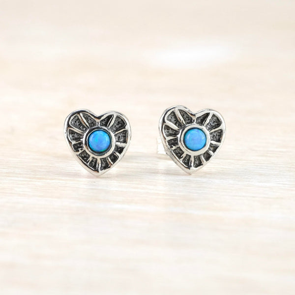Bright blue round opal stones are set within the centre of a silver heart shape. The silver is segmented with polished silver edges to each of the  twelve segments that surround the stone.