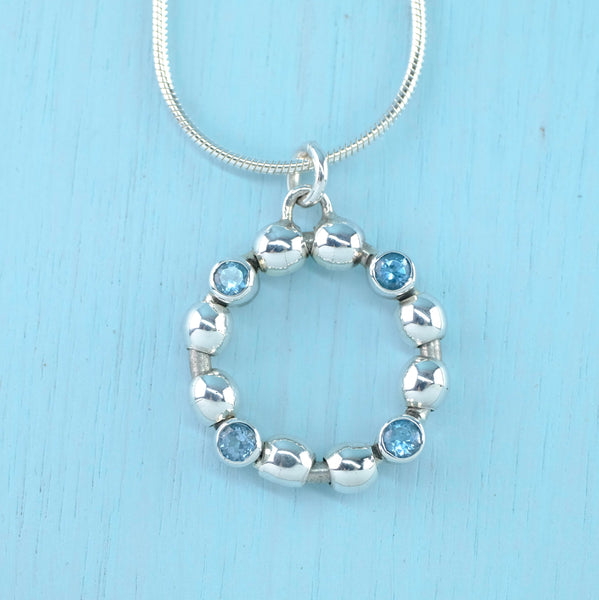 High Polished Sterling Silver and Blue Topaz Open Circle Pendant.