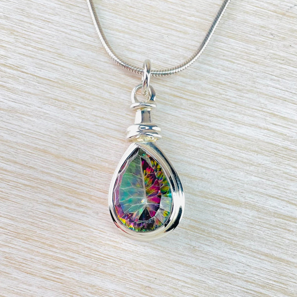 Tear drop mystic topaz stone is faceted showing pink/purple and green colours. Set in a silver frame with a chunky silver top and hanging from a silver bale 