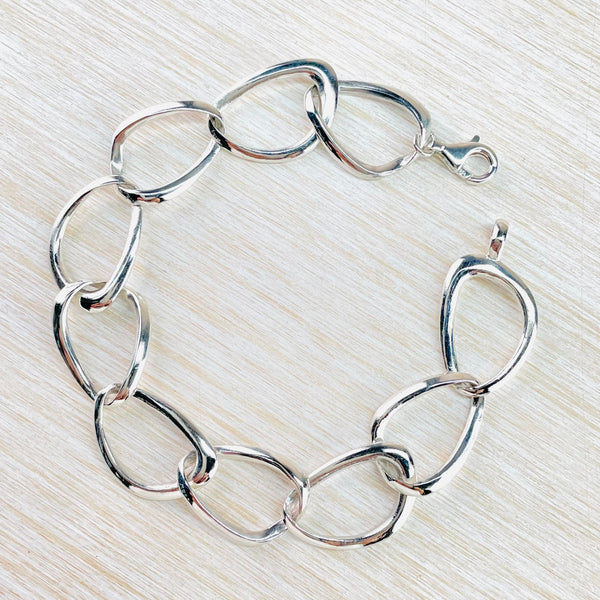 Ten large silver links joined together through each other . Each link has an inner tear drop shape with slightly squared off edges on the outside .