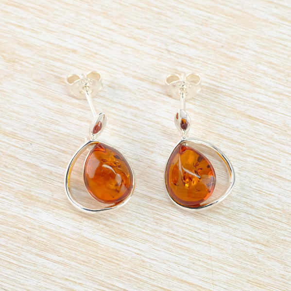 Bright sparkly amber with brown flecks within. The stones are teardrop shaped, surrounded with silver and then offset to one side of a silver tear drop outline.
