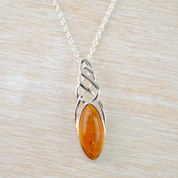 A clear amber stone in a marquise shape has a silver frame. This hangs below a celtic desgn knotin a vaguely triangle shape which comes half way down the sside of the stone