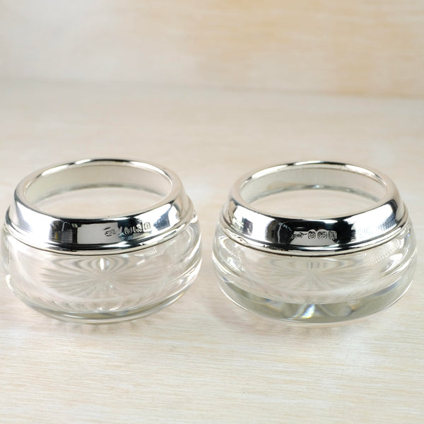 Small cut glass bowls are topped with a bright shiny silver rim, about a quarter the size of the bowl. The glass is cut with diamond shaped sections, come with star flowers cut in and others with a spotty design. Arranged in rows around the glass in alternate designs.