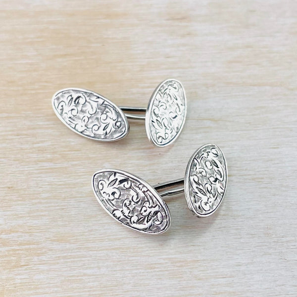 delicately decorated oval cufflinks. Each cufflink has two ovals connected by a silver bar.