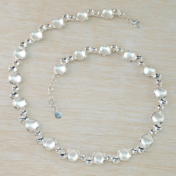 Necklace formed of concave discs in different sizes and finishes. In groups of three - a larger satin finished one then a medium and a small high polished. Discs go all around the necklace and it has a small piece of chain at the end.