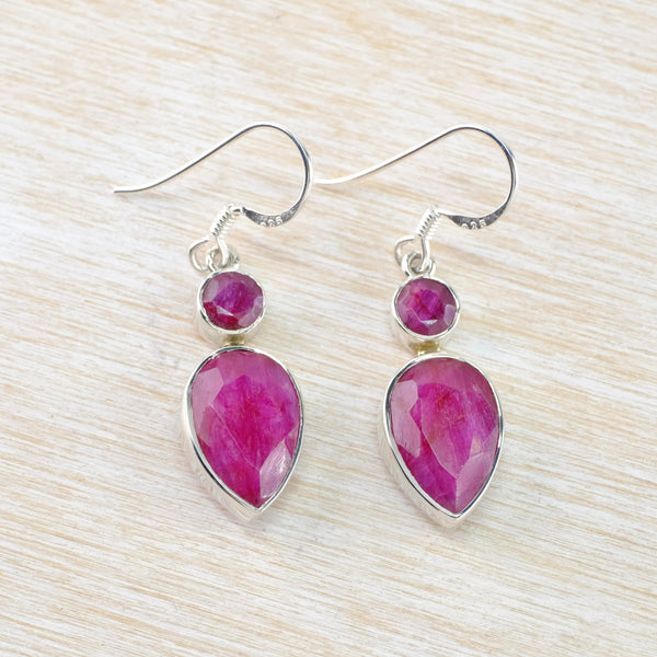 Deep pink faceted stones in a plain silver surround. Each earring is formed of two stones, a smaller round one at the top connected to a larger soft pear shape below. Hanging off a silver hook.