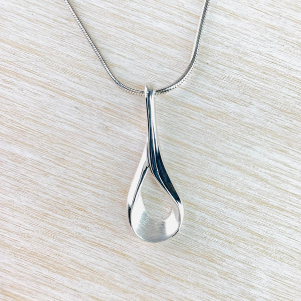 An open tear drop shape on a slender silver stem. The tear drop has a sarin inside with a polished outside. A silver snake chain threads through the top of the stem.
