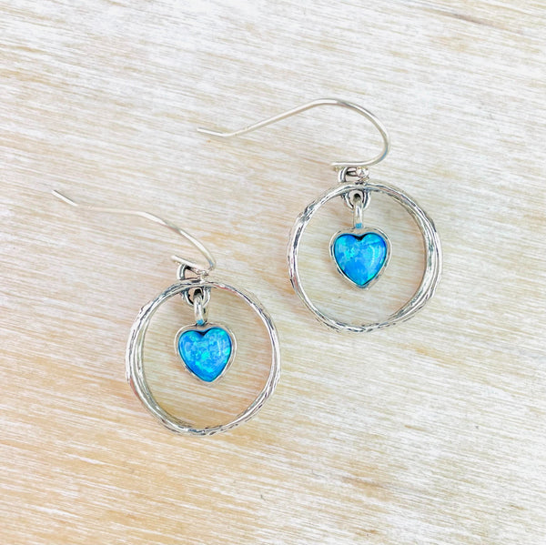 Bright blue opal hearts are suspended from a multi strand silver circle, hanging from a hook.
