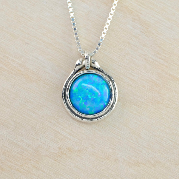 Pretty bright blue/green opal stone is set in a silver circle. The surround has two shiny circles and an oxidised central circle. 