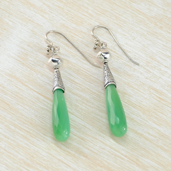 Long opaque, pale green tear drop shaped stone is set within a decorated silver casing - a bit like an upside down ice cream cone, below a silver sphere and a hook.