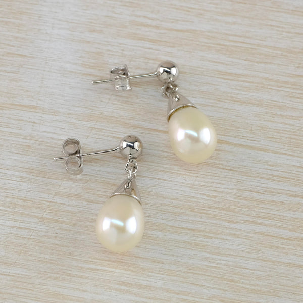 Very shiny glossy white round pearl hangs below a silver traingular shaped silver cap with a silver ball attaching the post and butterfly.