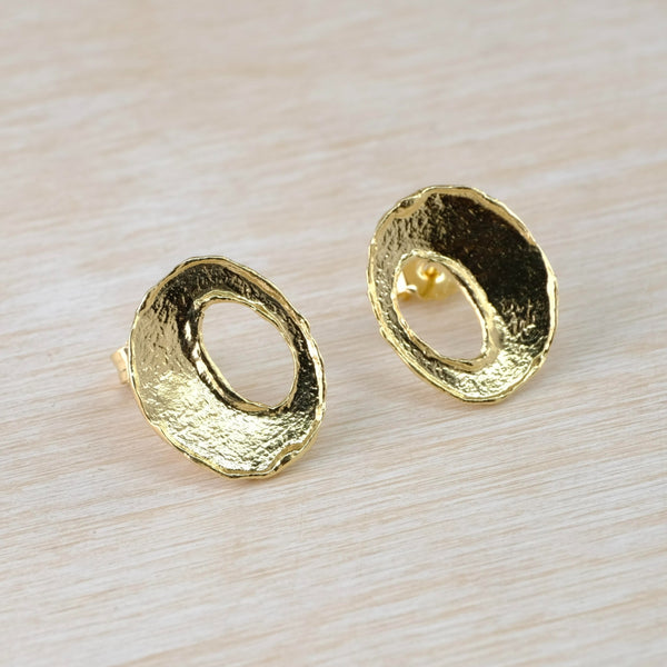 Each bright gold earring has a slight concave shape with a textured centre and polished edges. Sightly off central there is an oval cut out , about half the size of the earring. 