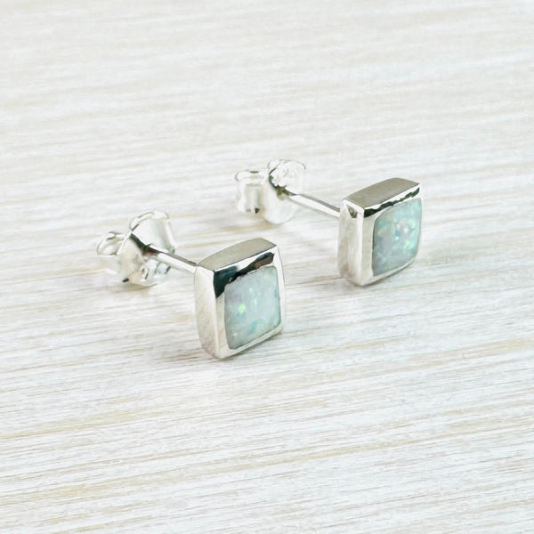 High polished silver squares with sparkly stones set flush to the silver. The stones show colurs of cream, green and pink. They have a silver stem and butterfly fillting attached at the back.