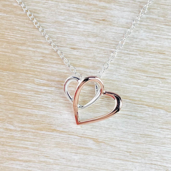 Twi interlocked hearts, one silve one rose gold colour are interlocked, The silver one is smaller than the gold.   