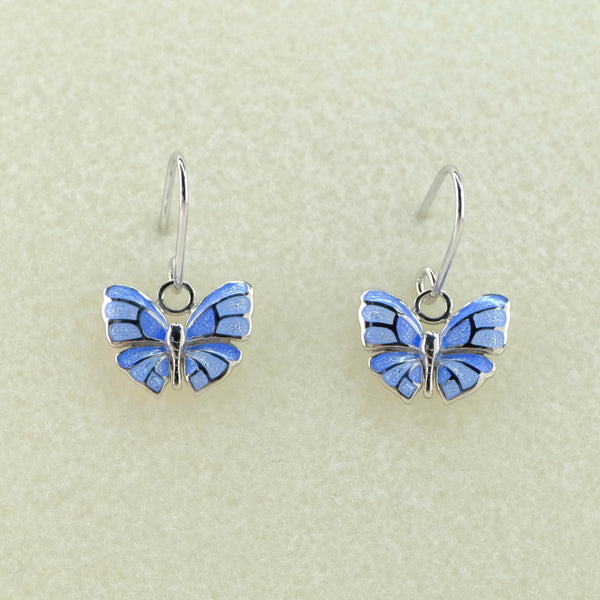 Butterfly design earrings with a silver body and silver edges and veins within the wings. Blue and pale lilac enamel forms the wings. Hanging off a silver hook.