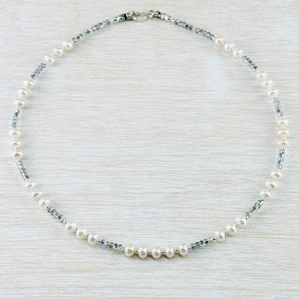 A symetrical design necklace with beads all the way round. All the pearl beads are the same size, all the crystal beads are smaller than the pearl but the same size as each other. The pattern of beads is four pearl at the front, then 4 crystal, 3 pearl . This pattern is repeated  four more times.
