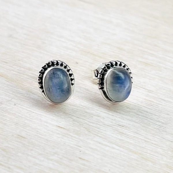 dark oval  blue rainbow moonstone set in a silver surround with little indentations as a decoration half the way around