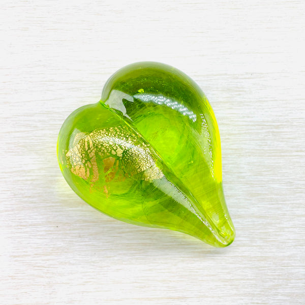 lime green glass heart shape with gold markings on the left hand side. The heart is 3D much like two cheeks.