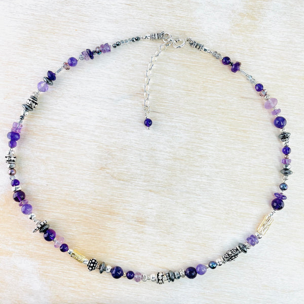 Light and dark purple beads, mostly round, are mixed with decorated silver beads - some tubes, some round, some polo shaped are arranged all the way around the necklace.