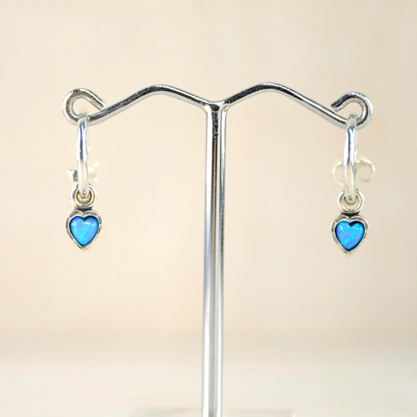 High polished silver in a three quarter hoop design with a silver ball at one end and a post and butterfly fitting at the other. Suspended from this is  a heart shaped bright blue opal stone set in a  silver frame.