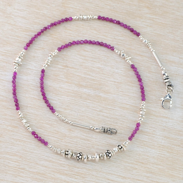 Small round ruby quartz beads in a pinky red shade are threaded in groups , alternating with groups of silver beads around the necklace. At the front are decorated silver beads with a slightly larger one in central position.