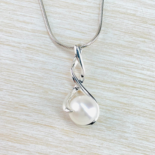 The silver has a double twist, one bit forms the bit the chain hangs through, the other holds the round pearl in place . The whole piece is almost a figure of eight with the bottom bit wider than the top.