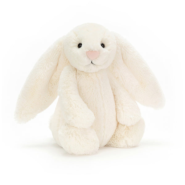 A very pretty cream bunny rabbit is sitting with her back legs stretched out and her front paws resting on her back feet. She has a little rounded tummy, long soft ears, a cute pink nose and little black eyes. She looks soft and cuddly!